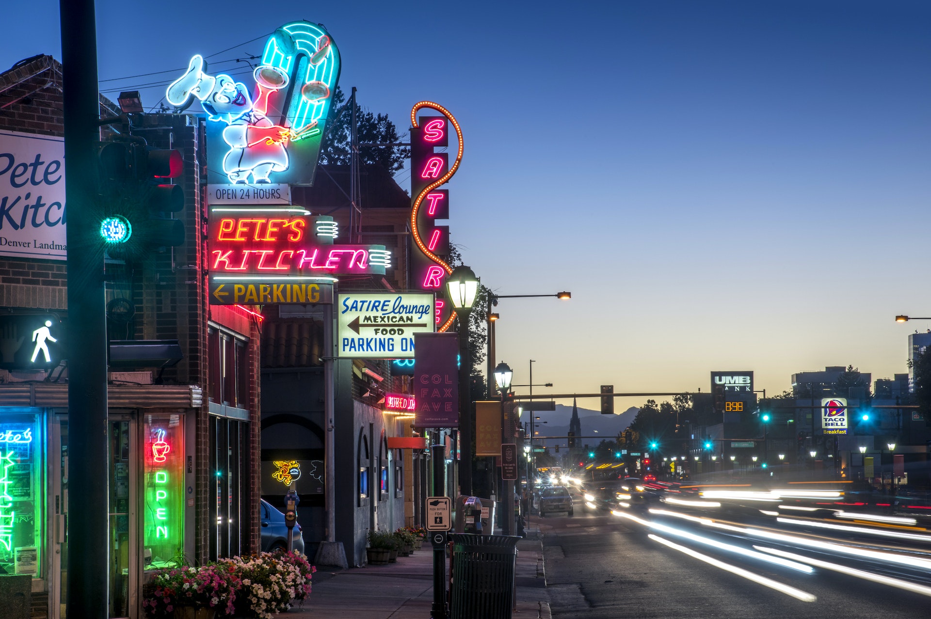 A strip of neon lights mark the way to a series of restaurants lining a road at night in a city