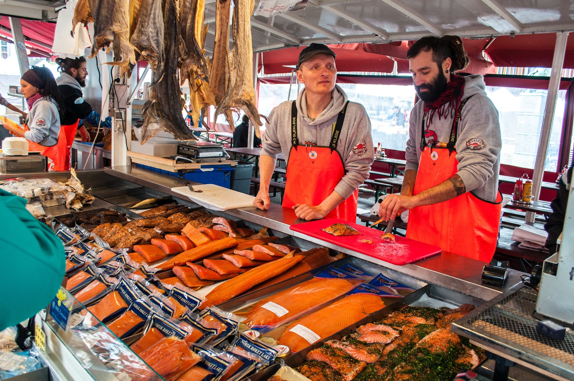 Two sellers of fresh fish at the fish market in red aprons in Begren